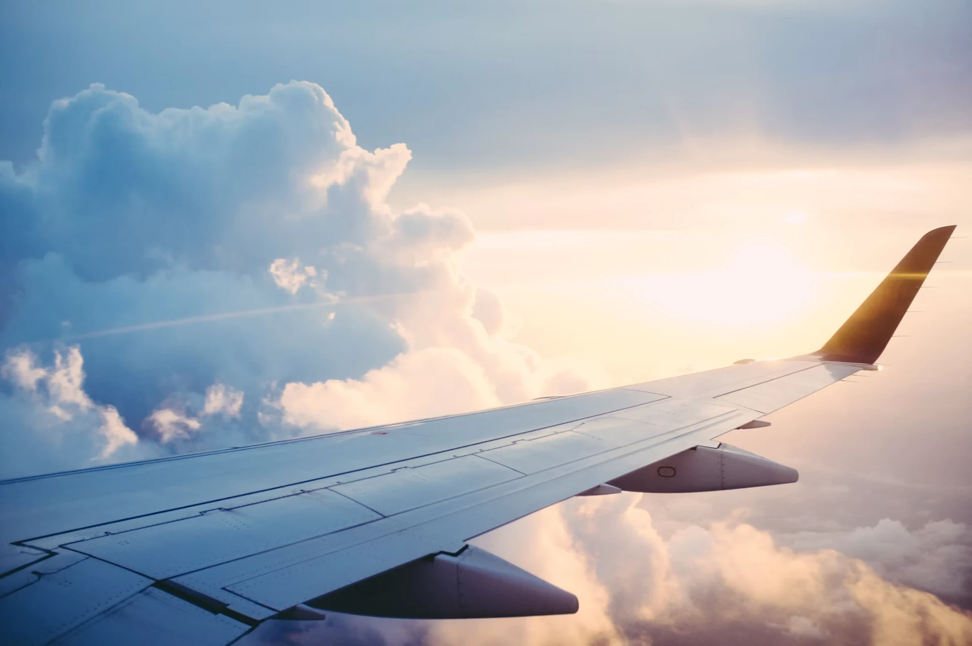 Vista da asa de um avião sobre as nuvens ao pôr do sol